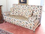 un canapé à motifs floraux dans un salon où se trouve un tapis au sol
