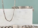 un bracelet en argent et une chaîne en argent posés sur une table blanche