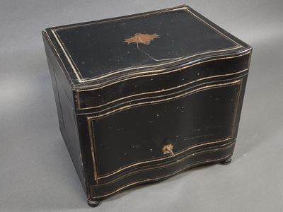 un vieux coffre noir orné d'un décor à la feuille d'or sur le devant