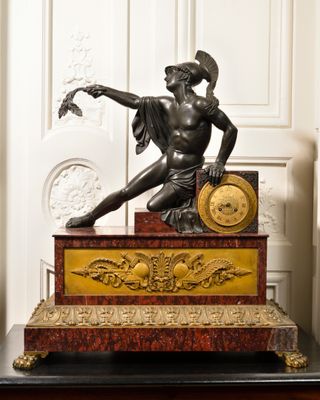 a statue of a man holding a clock on top of a table
