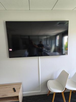 two white chairs in a room with a flat screen tv on the wall
