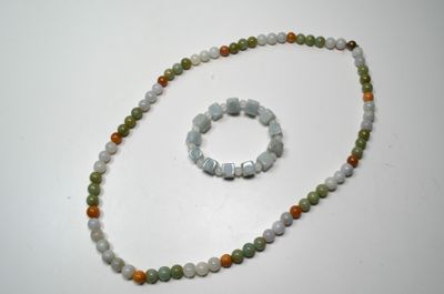 collier et bracelet composés de perles vertes et orange sur un fond blanc