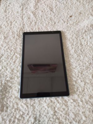 une tablette noire posée sur une couverture blanche