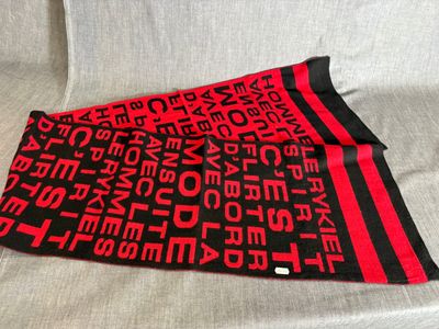 une écharpe rouge et noire avec des inscriptions, posée sur un canapé