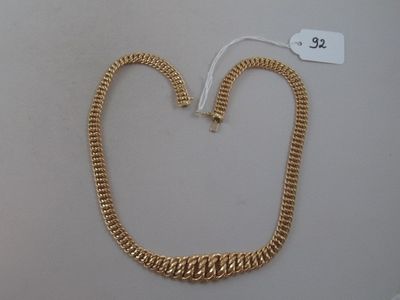 a close up of a gold necklace on a white surface