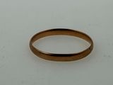 a close up of a gold wedding ring on a white surface