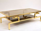 une table basse dorée avec un plateau en verre sur fond blanc