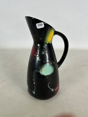 un pichet noir orné d'un motif jaune et rouge