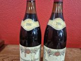 Deux bouteilles de vin sont posées sur une table devant un mur rouge.