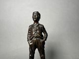 bronze statue of a man standing on a base with his hands in his pockets