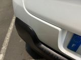 a white car parked in a parking lot with a blue sticker on the bumper