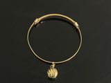 un bracelet rigide en or orné d'une boule en or sur fond noir
