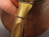 a person holding a brass pot with a handle