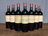 six bottles of red wine are lined up on a wooden table