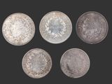 six pièces d'argent de tailles et de formes différentes sur fond noir