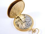 a gold pocket watch that is open on a white surface