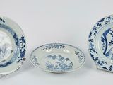 trois assiettes bleues et blanches et un bol posés sur un plan de travail blanc