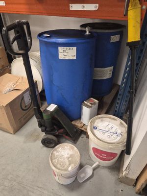 un fût bleu posé à côté d'un seau bleu sur une palette dans un garage