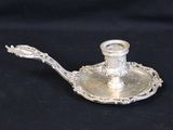 an antique silver plate with a candle holder on a black background