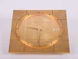 une horloge en bois avec un cadran doré sur un fond blanc