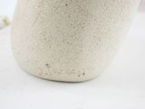 a white vase sitting on a white table with a flower in it