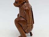 an old wooden figurine of a monkey sitting on a chair