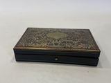 an old black and gold box sitting on top of a white table