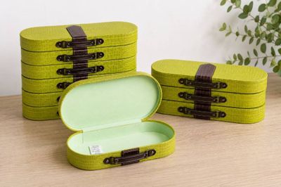Trois boîtes vertes sont posées sur une table, avec une plante en arrière-plan.
