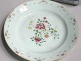 a white plate with pink flowers on it next to a blue and white vase