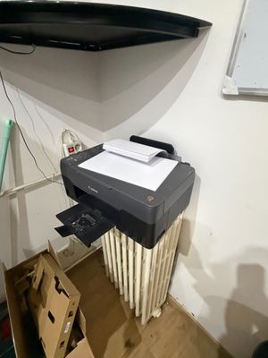 a printer sitting on top of a radiator in the corner of a room