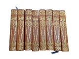 six old books are lined up in a row on a white surface