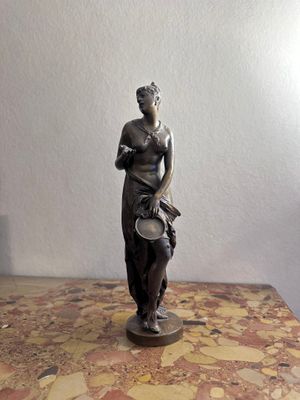une statue représentant une femme tenant un bol posé sur une table
