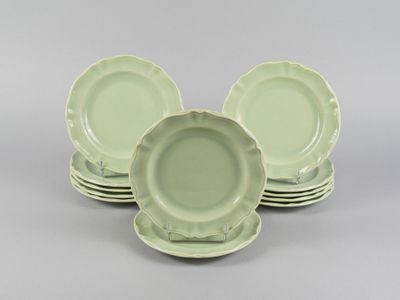 six green dinner plates stacked on top of each other on a gray surface