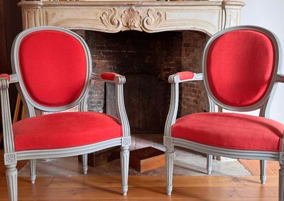 two red chairs sitting next to each other in front of a fireplace