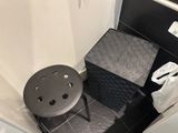 a small stool in the corner of a small bathroom
