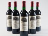 four bottles of red wine are lined up on a white surface