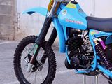 a blue dirt bike parked on a stand in a parking lot