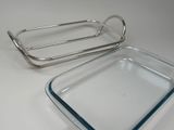 two rectangular glass dishes with metal handles on a white surface