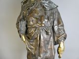 une statue en bronze représentant un homme portant un chapeau et un manteau