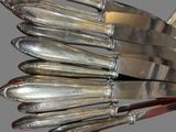 a lot of silver knives that are on a rack