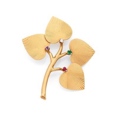 un gros plan d'une broche en or ornée de feuilles et de pierres précieuses