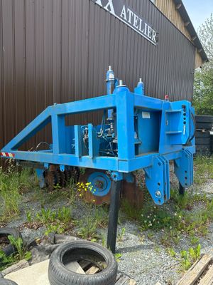une remorque bleue à laquelle est attaché un pneu, garée devant un immeuble