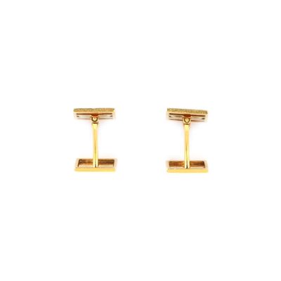 une paire de boutons de manchette en or sur fond blanc