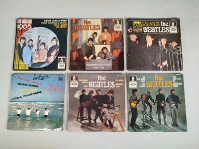 six beatles album covers on a white table top