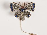 une image représentant une broche en forme de papillon ornée de pierres bleues et blanches