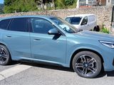 bmw x1 suv parked on the side of the road in front of a stone wall