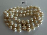two strands of white pearls with a gold clasp on a white surface