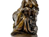 an image of a bronze statue of a woman sitting on a rock