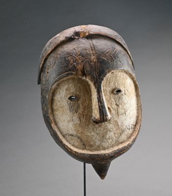 un gros plan d'un masque en bois posé sur un socle