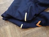 navy blue pants with orange stripes on a wooden floor next to a pair of shoes